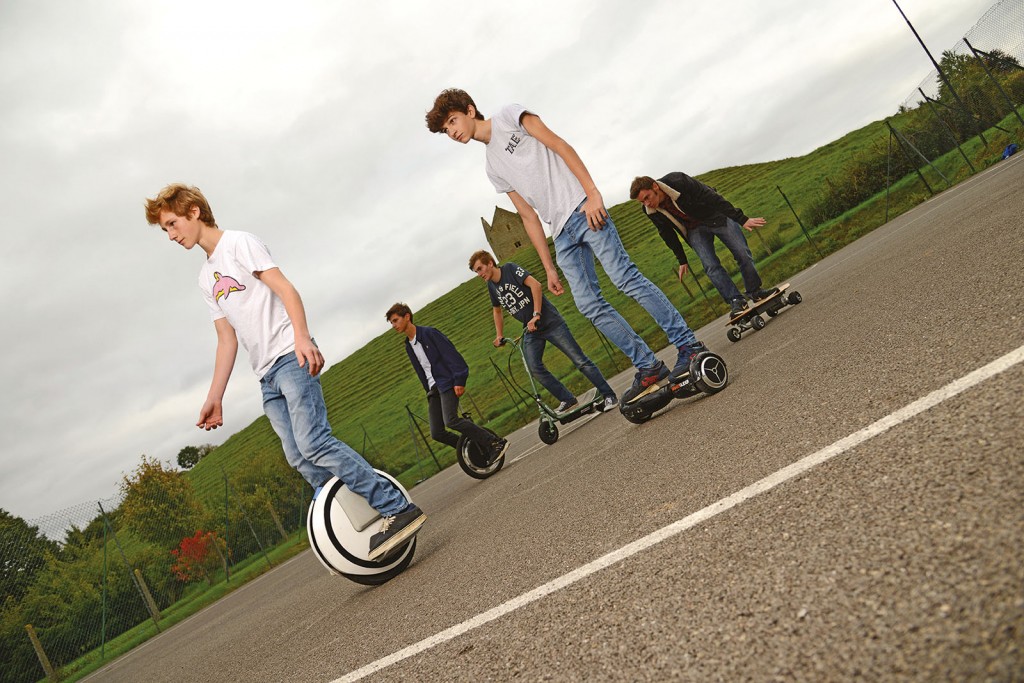 Location shot of teenagers riding a variety of rideables in a park. You'll notice Jack looking very natural at the back.