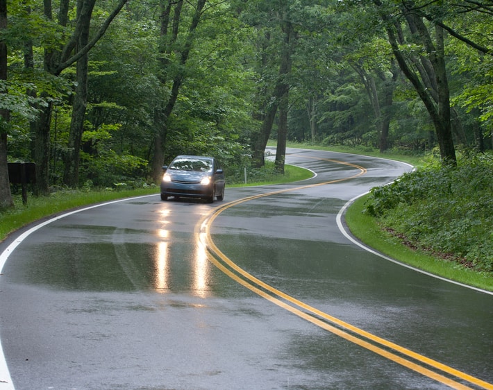hatchback-driving-down-winding-wet-road
