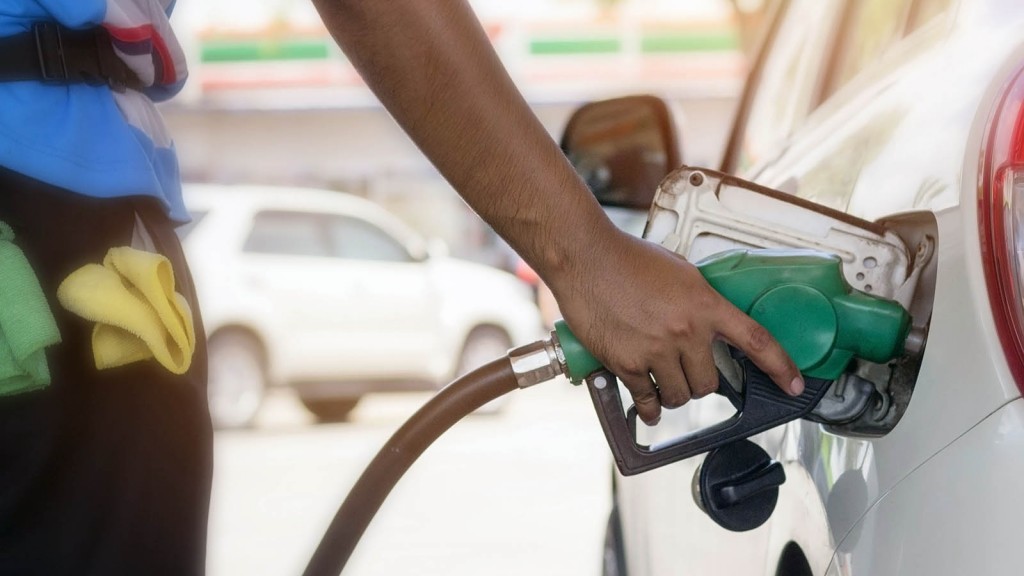 white car refueling gasoline by auto dispenser nozzle at petrol station with warm sunlight