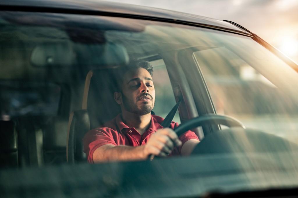 Middle Eastern man falling a sleep while driving a car.