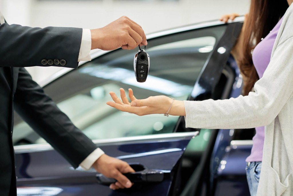 Salesman giving key to female car buyer